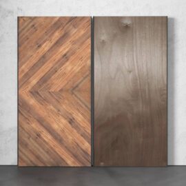 Two vertically positioned panels against a gray wall. The left panel is the Lucas 83" x 40" Reclaimed Wood Arrow Barn Door, featuring a herringbone pattern, while the right panel has a smooth, plain finish.