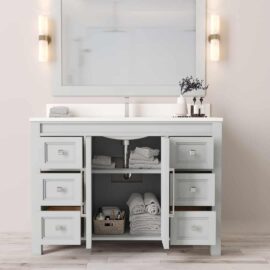The Belluno 48" Single Sink Vanity features a large mirror, light fixtures, multiple shelves and drawers, neatly folded towels, a potted plant, and a basket with toiletries underneath the sink.