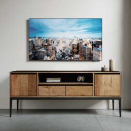 A modern living room featuring a Kolt 60" Wide TV Stand beneath a wall-mounted flat-screen TV displaying a cityscape. Minimalistic decor, including small vases and a book, is tastefully arranged on the stand.