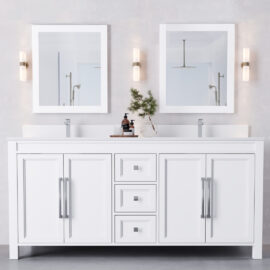The Belluno 72" double-sink bathroom vanity features white cabinetry, two rectangular mirrors, and wall-mounted lights. Items on the counter include soap dispensers and a small plant.