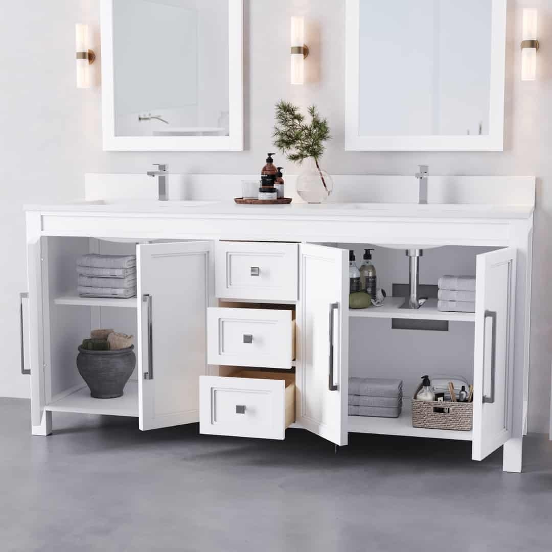 The Belluno 72" Double Sink Vanity boasts white cabinets with open doors that reveal neatly folded towels, a potted plant, and essential bathroom items. Above the vanity, two sinks are flanked by mirrors and illuminated by wall-mounted lights.