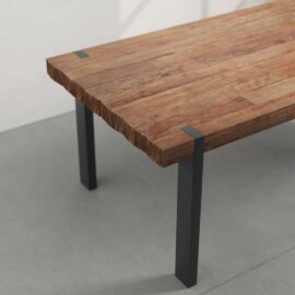 The Beam Dining Table features a rectangular wooden top with black metal legs, resting elegantly on a light grey floor. The table boasts a natural, unfinished edge and a smooth surface, making it both rustic and modern.
