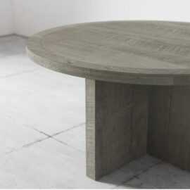The Camden Round Dining Table in Rustic Grey stands on a tiled floor in a minimalistic room.