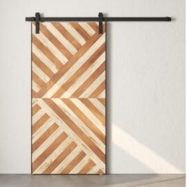 The Celestia Reclaimed Wood Barn Door, featuring a diagonal stripe pattern in light and dark wood tones, is mounted on a black metal track against a plain white wall.