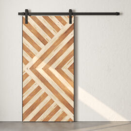 A reclaimed wood sliding barn door with a geometric, diagonal stripe pattern stands against a plain, light-colored wall. The rustic charm of the barn door adds character to the white backdrop, creating a striking visual contrast.