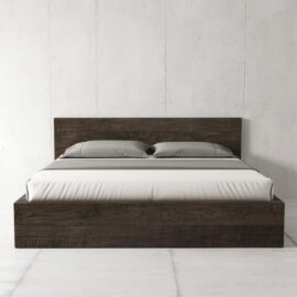 The Lugano Bed in Café Noire, a modern platform bed with a headboard, features white bedding and two gray pillows, all set against a plain white wall.
