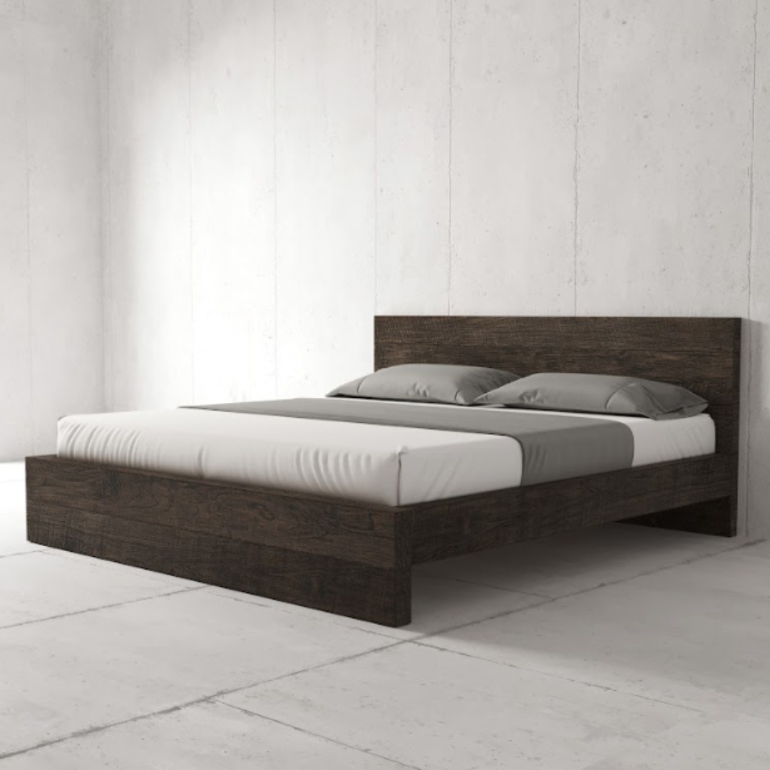 A minimalist Lugano Bed (Café Noire) with a headboard in a plain, concrete-walled room. The bed is dressed in neutral-toned bedding and two gray pillows.