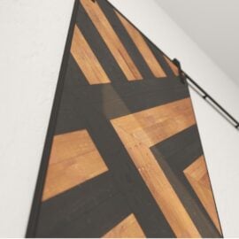 Close-up of the Lumina Reclaimed Wood Barn Door Espresso with a geometric design featuring diagonal wooden and black-painted panels.