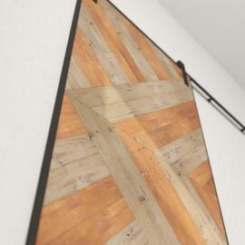 A close-up view of a sliding barn door with a chevron pattern, crafted from reclaimed wood and mounted on a black metal track.
