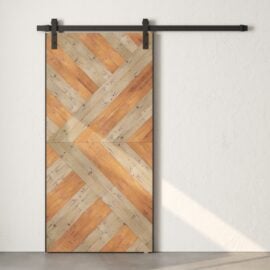 A sliding barn door with a chevron wood pattern, crafted from reclaimed wood, is mounted on a white wall.