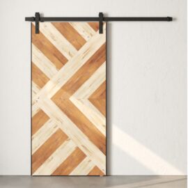 The Lumina Reclaimed Wood Barn Door White, featuring a chevron pattern, is mounted on a black metal track against a white wall.