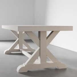 A Madera Dining Table - Pure White with an X-shaped support structure rests on a light gray floor against a plain white wall.