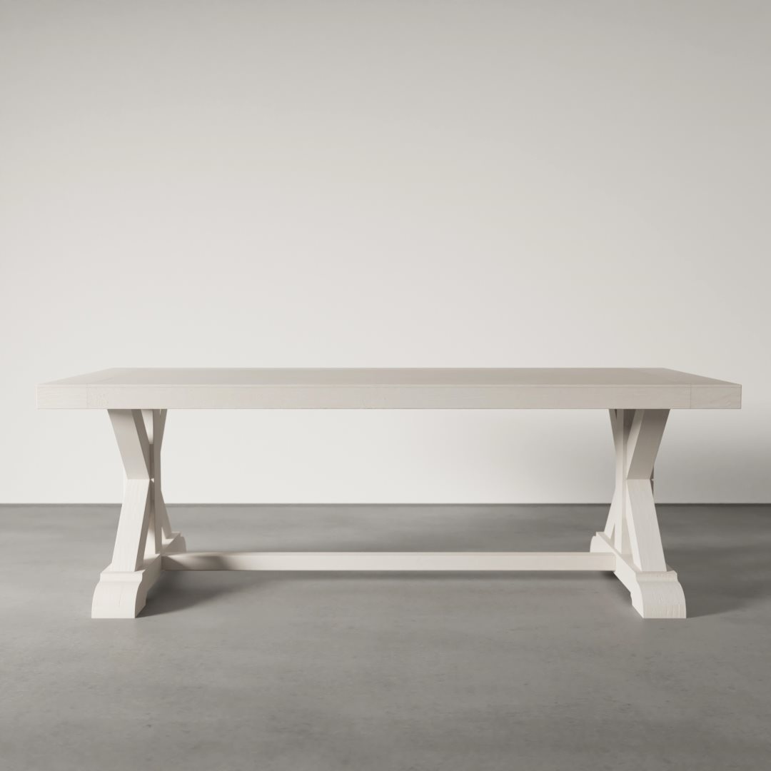 The Madera Dining Table - Pure White, featuring a rectangular design and an X-shaped base, stands on a gray concrete floor against a plain light-colored wall.