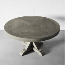 Introducing the Madera Round Table - Café Noire, a round, grey wooden table featuring an elegant geometric X pattern on its surface and supported by a stylish pedestal base.