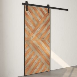 The Celestia Reclaimed Wood Barn Door (Grey) features a chevron-patterned design in light and dark tones, mounted on a black metal track against a light-colored wall.