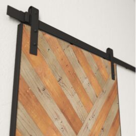 Close-up view of the Celestia Reclaimed Wood Barn Door (Grey) featuring a chevron pattern made from wood planks in various shades, mounted on a black metal track.