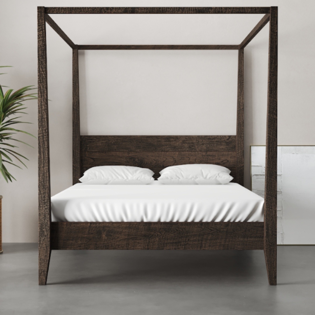 A Riviera Bed (Café Noire) with white bedding is situated in a minimalist room with a light-gray floor, a potted plant, and a framed picture leaning against the wall.