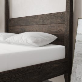 A Riviera Bed (Café Noire) with white bedding and pillows is next to a large leaning mirror with a wooden frame.