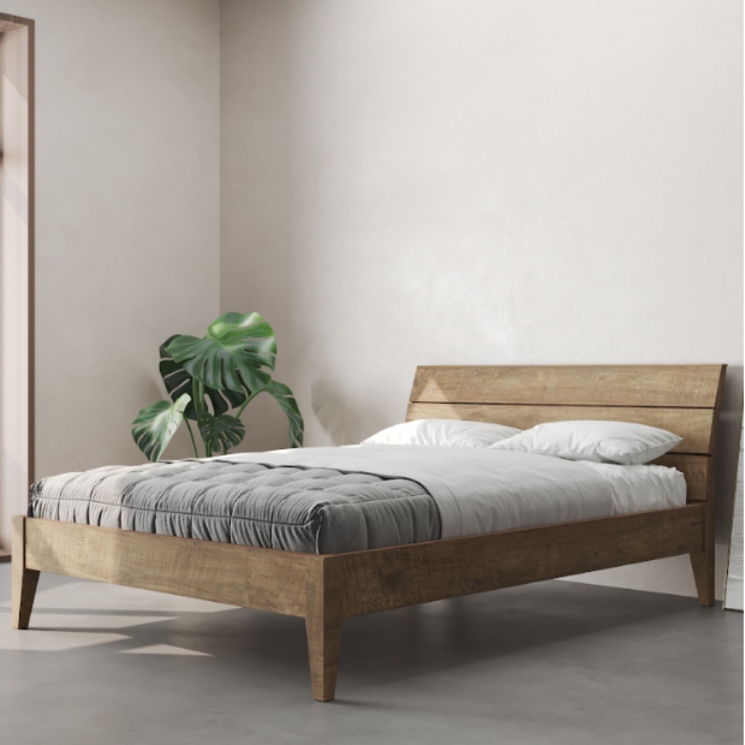 A minimalist bedroom features the Tuscan Bed (Natural) with white bedding and a gray blanket. A green potted plant is positioned next to the bed against a light-colored wall.