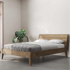 A minimalist bedroom features the Tuscan Bed (Natural) with white bedding and a gray blanket. A green potted plant is positioned next to the bed against a light-colored wall.