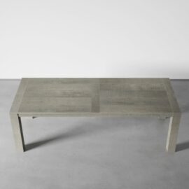 A grey rectangular wooden villa dining table with a minimalist design stands elegantly on a light grey concrete floor, adding a touch of rustic charm.