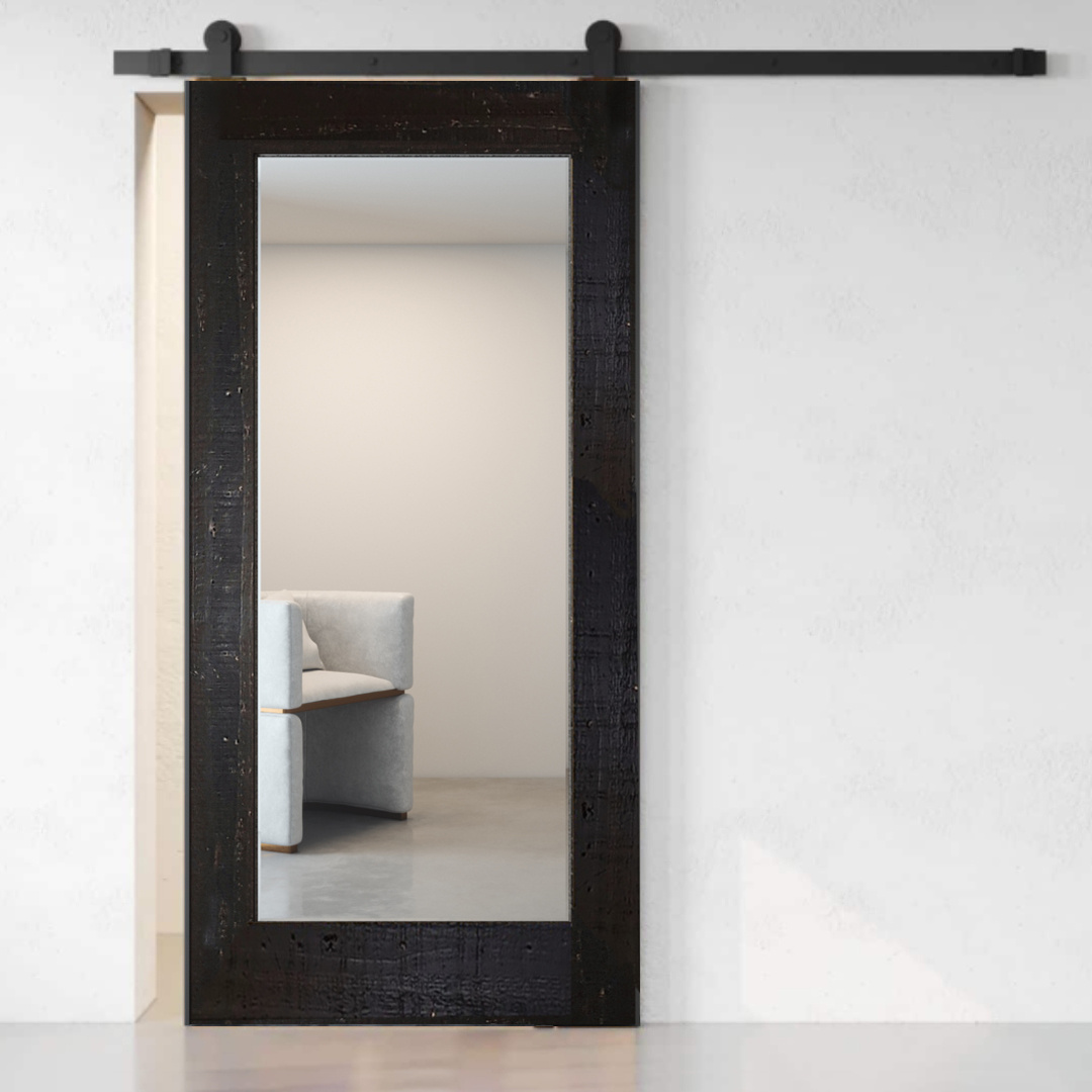 A partially open Beveled Mirror Barn Door (White Wash) reveals a glimpse of a corner of a modern, minimalist room with light-colored furniture in the background.
