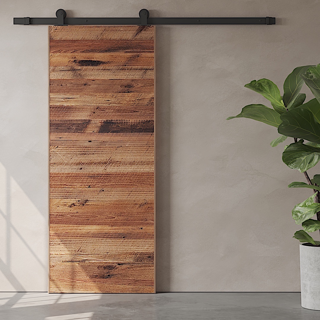 A Horizontal Door Slab crafted from reclaimed wood is mounted on a black metal track, positioned next to a green potted plant against a beige wall.