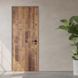 A Vertical Door Slab with a black handle is set in a light-colored wall. A potted green plant is partially visible to the right.