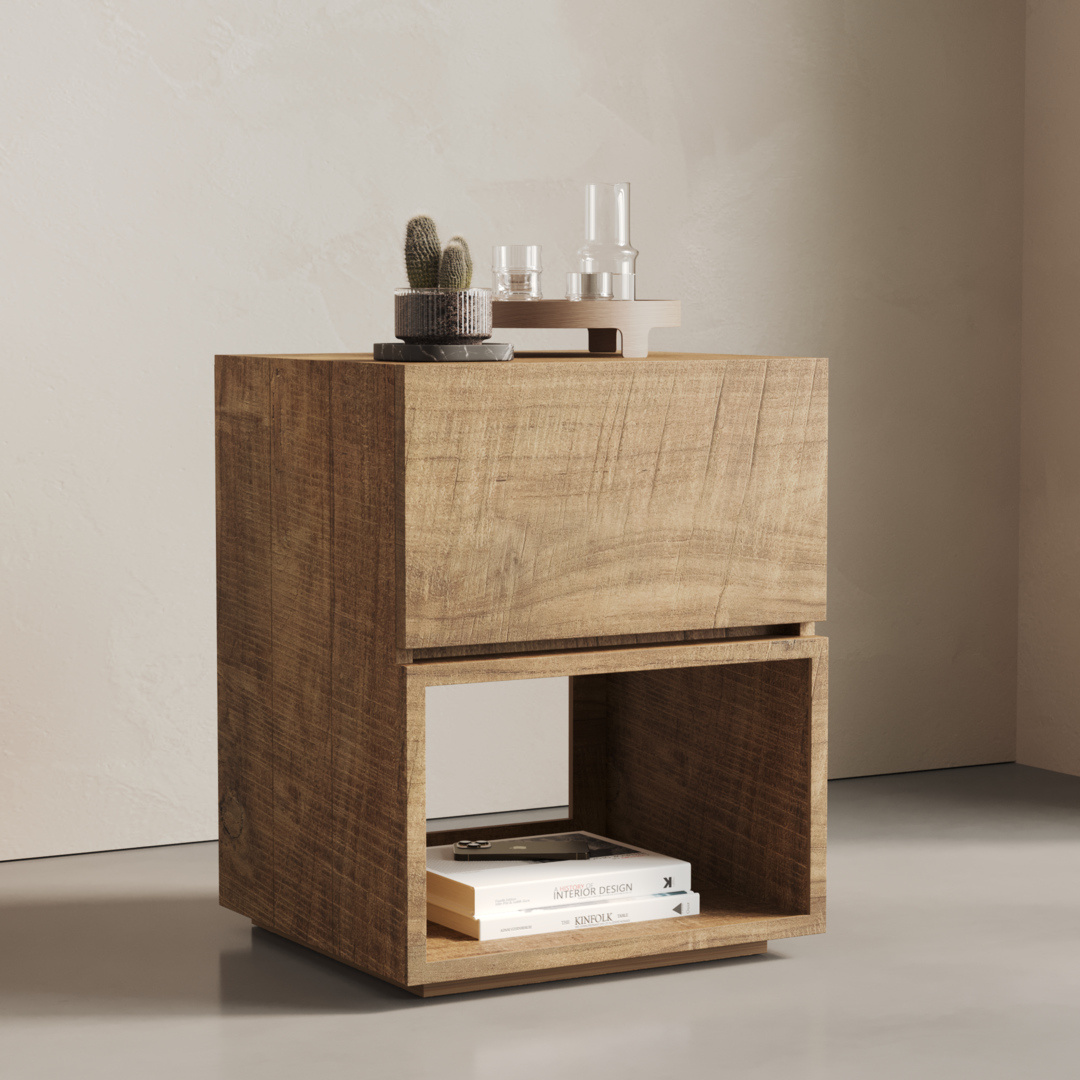 The Burma Nightstand features two compartments; its top surface is adorned with a small cactus, two glass containers, and a tray. The lower compartment holds books. It sits against a neutral-colored wall and on a gray floor.