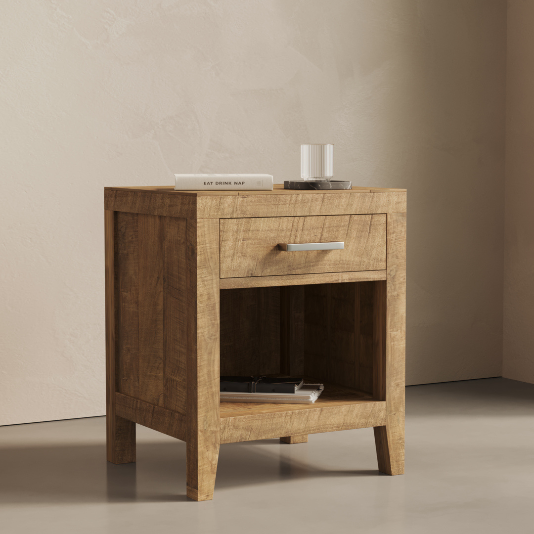 The Riviera Nightstand, featuring a closed drawer and an open lower shelf, is adorned with a glass of water, a book, and a small dish on top. It is positioned against a plain wall on a smooth floor.