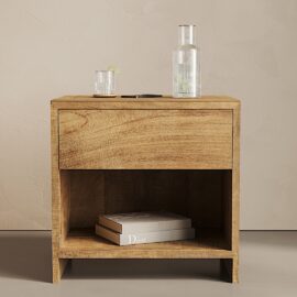 A Satillo Nightstand with one drawer and an open shelf. On top are a glass of drink with a lime, a bottle of water, and a smartphone. Inside the shelf are a few books, one titled "Dior.