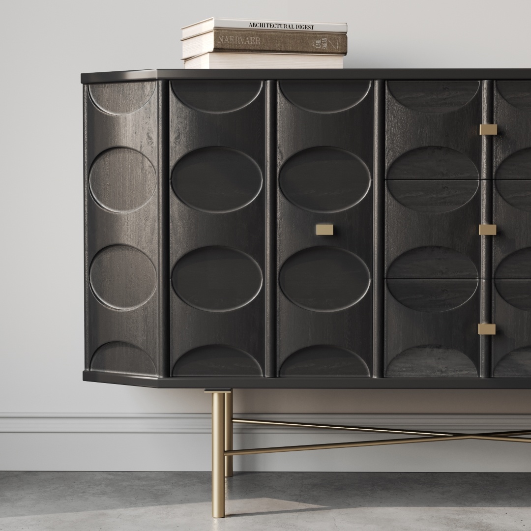 Alba 60 Side Cabinet-b An Alba 60" Side Cabinet with dark, oval-patterned cabinet doors sits against a white wall. A book titled "Architectural Digest" rests on top, while gold legs support the piece over a light-colored floor.