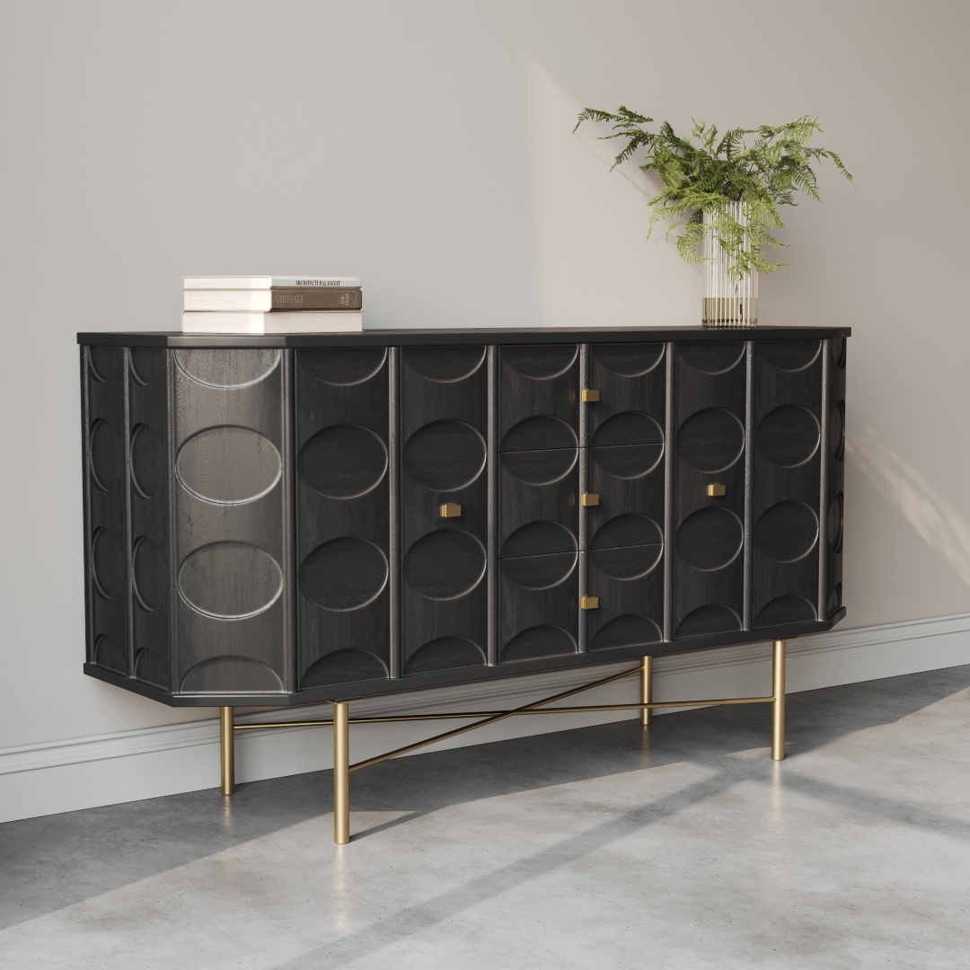 Alba 60 Side Cabinet-d The Alba 60" Side Cabinet showcases black circular patterns, accented by gold handles and legs, standing gracefully against a light wall. A potted fern and a stack of books embellish the top, while the room's concrete floor enhances its modern appeal.