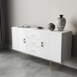 An Arista 60" Side Cabinet in White Wash with textured doors and gold handles stands elegantly against a light-colored wall. It showcases two decorative vases and a stack of books, providing both style and functionality in this chic space.