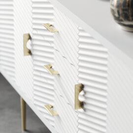 Detailed view of the Arista 60" Side Cabinet (White Wash), highlighting its gold handles and legs. A ceramic vase is partially visible on top.