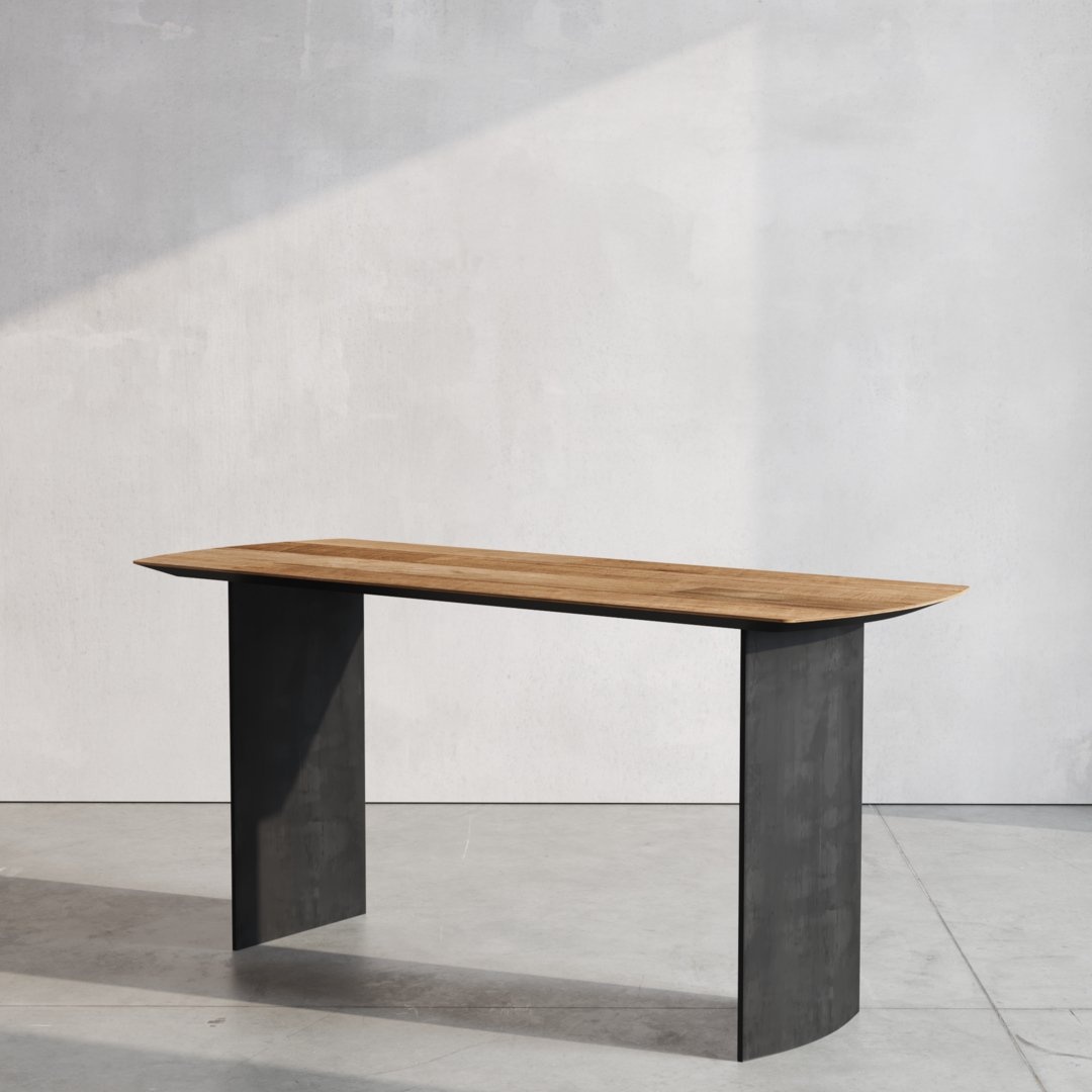 The Atelier Desk, featuring a modern wooden top and two black rectangular supports, stands on a concrete floor against a plain, light-colored wall. Light casts a shadow on the wall.