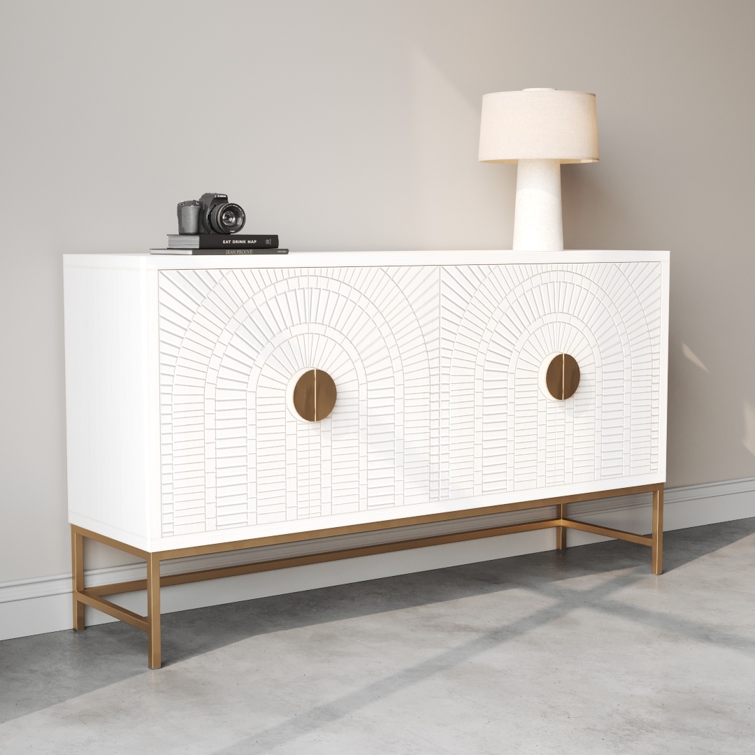 Coral 60 Side Cabinet -c This 60" Coral Side Cabinet features a white finish with a geometric pattern, golden knobs, and stand. It is topped with a camera, books, and a beige lamp and stands against a light-colored wall, making an elegant addition to any room.