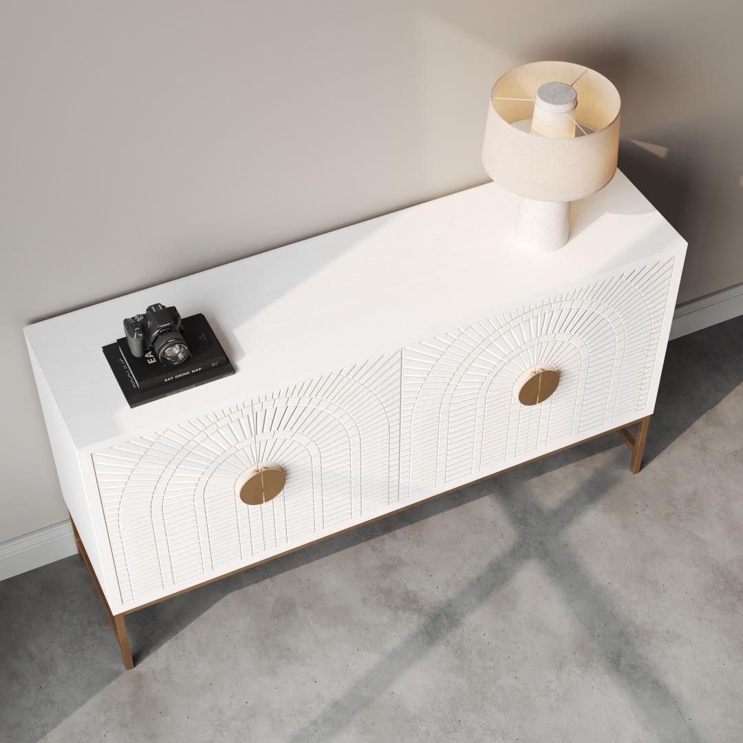 Coral 60 Side Cabinet -d The Coral 60" Side Cabinet in white, featuring two drawers with circular handles and adorned with a lamp and a camera placed on top of a book, stands against a light gray wall. Shadows cast from nearby windows are visible on the floor.