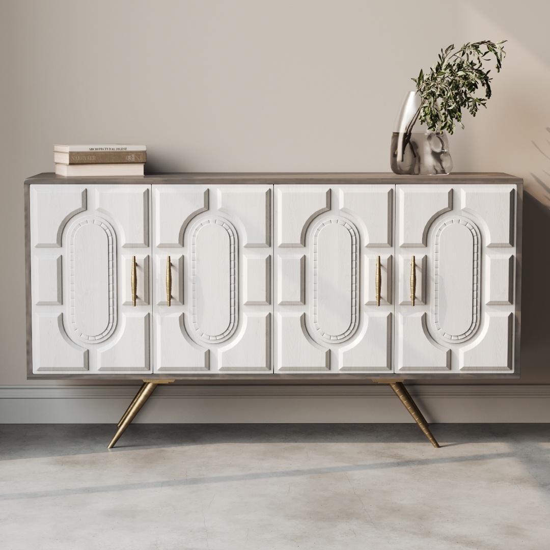The Lugo 60" Side Cabinet, a white rectangular sideboard showcasing ornate geometric patterns, features gold handles and tapered gold legs. Placed against a beige wall, it is stylishly adorned with books and a vase holding greenery.
