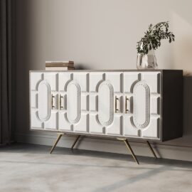 The Lugo 60" Side Cabinet is a white sideboard featuring geometric panel designs and gold handles, mounted on angled legs. Atop the cabinet, you'll find a vase with greenery and a stack of books.