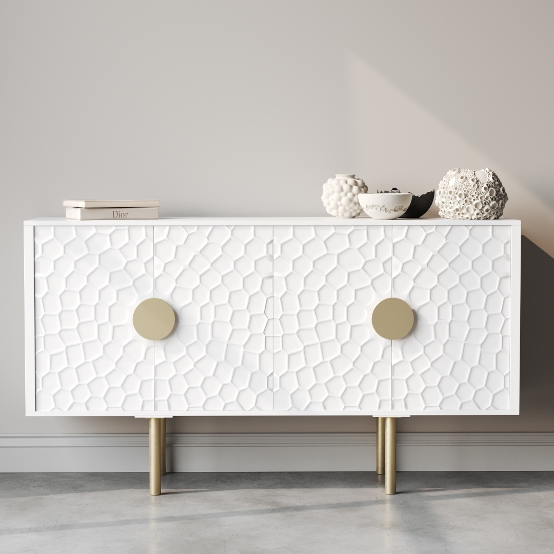 The Luna 60" Side Cabinet, adorned with a geometric pattern and featuring two large round handles and gold legs, stands against a light gray wall. It is elegantly topped with three decorative objects and books.