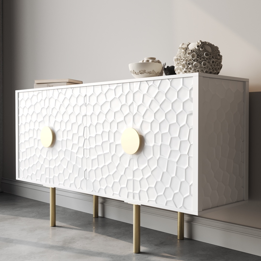Luna 60 Side Cabinet-d The Luna 60" Side Cabinet features a white sideboard adorned with a striking hexagonal pattern on its doors and accented by large round gold handles. It stands gracefully on slender gold legs and is topped with decorative items such as a coral display and a bowl.