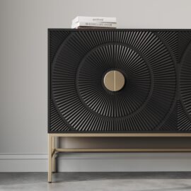 A black, textured Orbita 60" Side Cabinet with circular patterns on the doors, two central handles, and a metallic frame stands against a gray wall. Three books are placed on top. This sideboard seamlessly combines style and functionality.