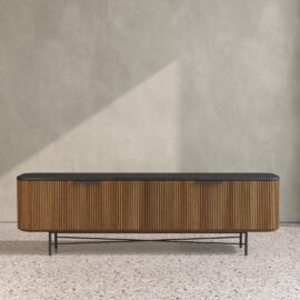 The Osaka Wide TV Stand with a black top stands against a textured beige wall on a terrazzo floor.