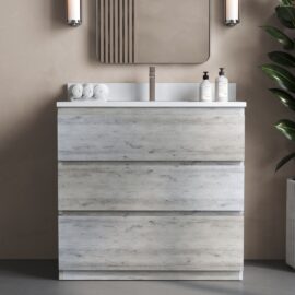A Vamo Bathroom Vanity featuring a rustic grey 36" single sink vanity, complemented by a rectangular mirror, light wood-grain drawers, and a pristine white countertop. Two rolled towels and two bottles rest on the counter, while a plant adds a touch of greenery next to the vanity.