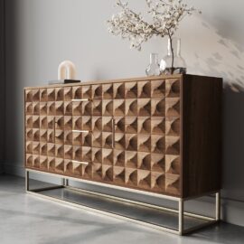 The Wadi 57" Side Cabinet boasts an intricate geometric pattern on its wooden drawers, complemented by metallic handles. Adorned with decorative glass vases and a small lamp on top, this sideboard looks stunning against a light grey wall.