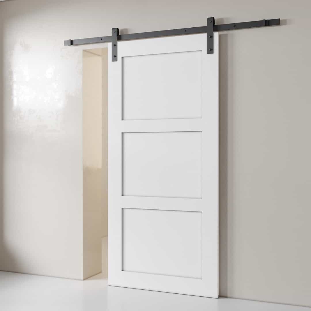 3-Panel-White-2.jpg A 3-Panel Barn Door, featuring a white finish and enclosed in three rectangular sections, is installed on a black metal track mounted against a light-colored wall.