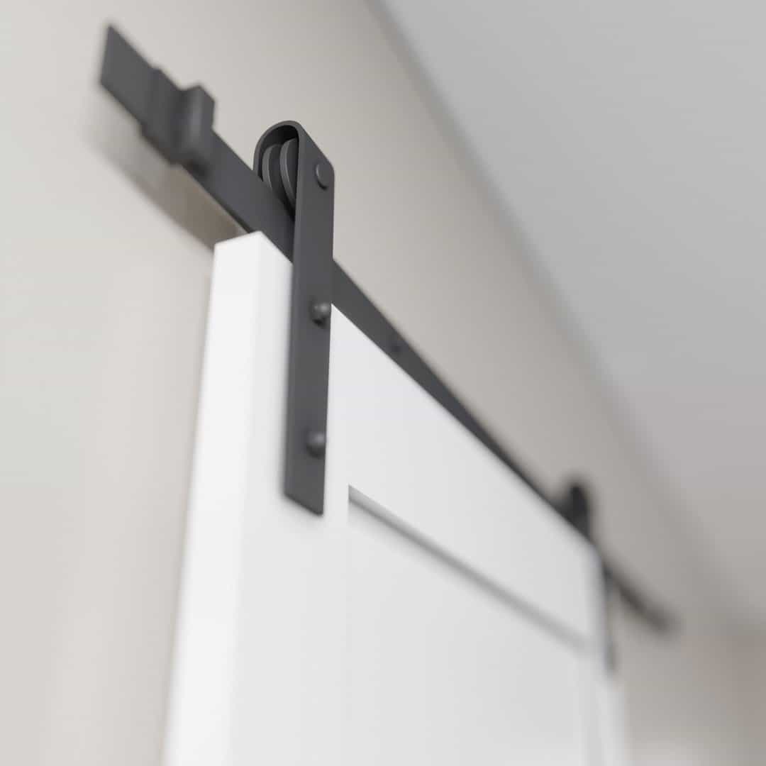 3-Panel-White-3.jpg A close-up view of a 3-Panel Barn Door in white, suspended from a black metal track system against a light-colored wall.