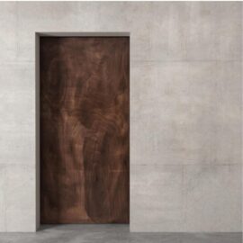 The Alchemist Herringbone Barn Door, a wooden door set within a concrete wall, creates a minimalist architectural design.