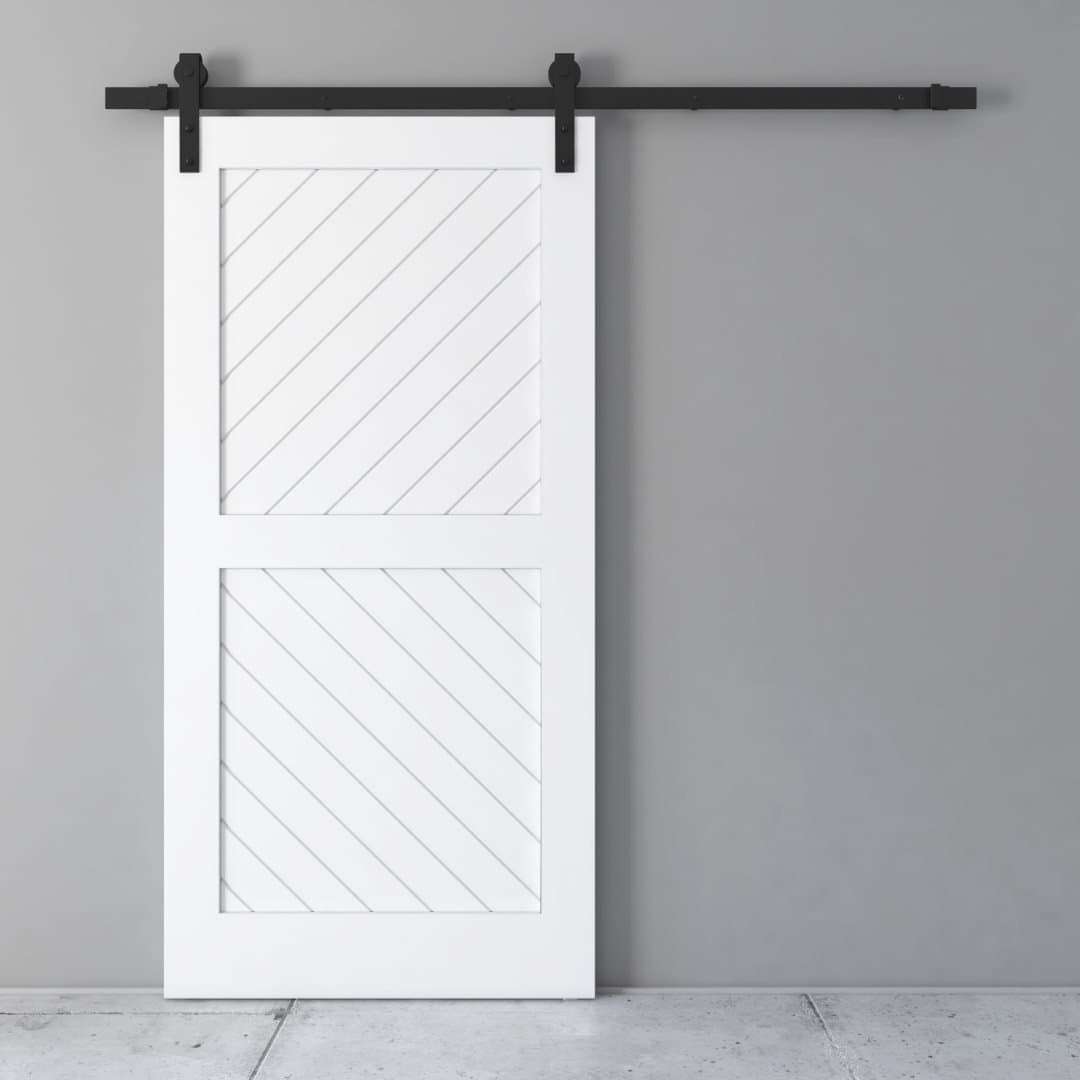 A Cabana Barn Door in white, featuring diagonal panel designs, mounted on a black track against a gray wall and a concrete floor.